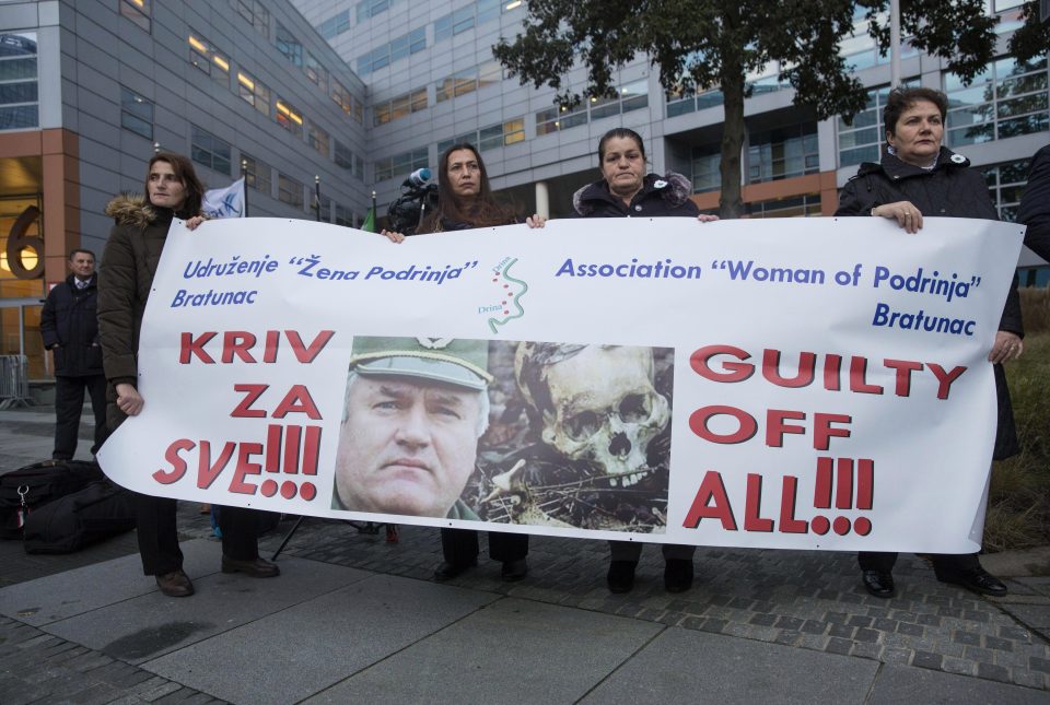 Protesters hold up a banner accusing Mladic of war crimes outside the court
