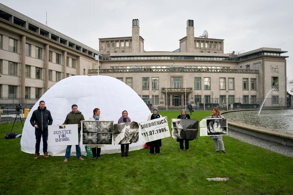Demonstrators hold up banners and photos outside the tribunal