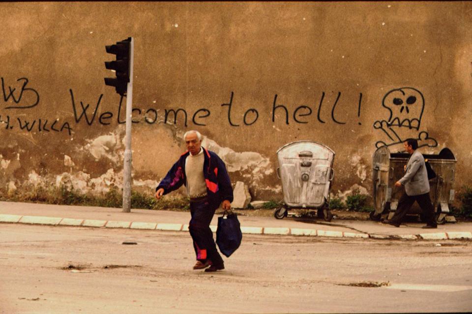 A man runs across the road to dodge snipers during the Bosnian War 