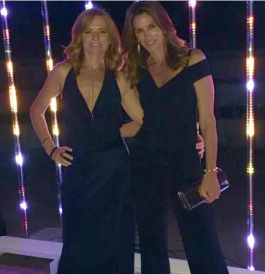 Two women in black jumpsuits posing together.