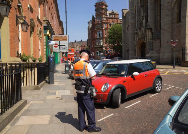 In Leeds, a traffic warden hands out a parking ticket, a practice the AA says has become out of control