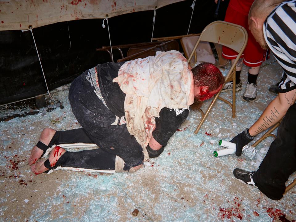  Jesse F***ing Amato kneeling and resting on a metal chair after being thrown out of the ring on to glass-covered concrete