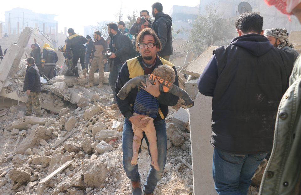 A man carries a wounded child during the search and rescue operation at Sekba 