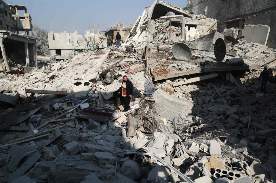 Civilians look for victims under the rubble following a reported air strike on the rebel-held town of Hamouria