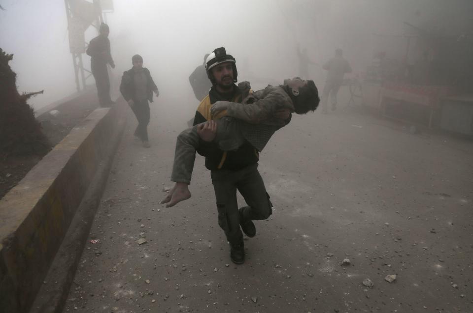 A White Helmet volunteer carries a wounded boy after digging him out of the rubble