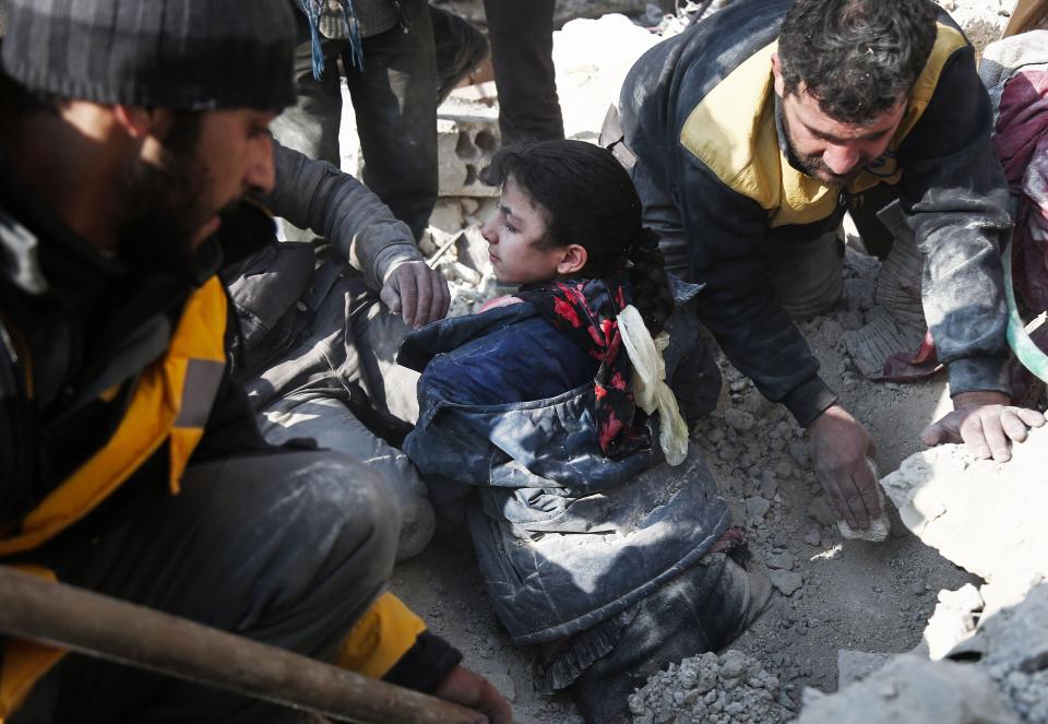 White Helmets volunteers dig a girl out of the rubble following an air strike on Hamouria, in the besieged rebel-held Eastern Ghouta area near Damascus