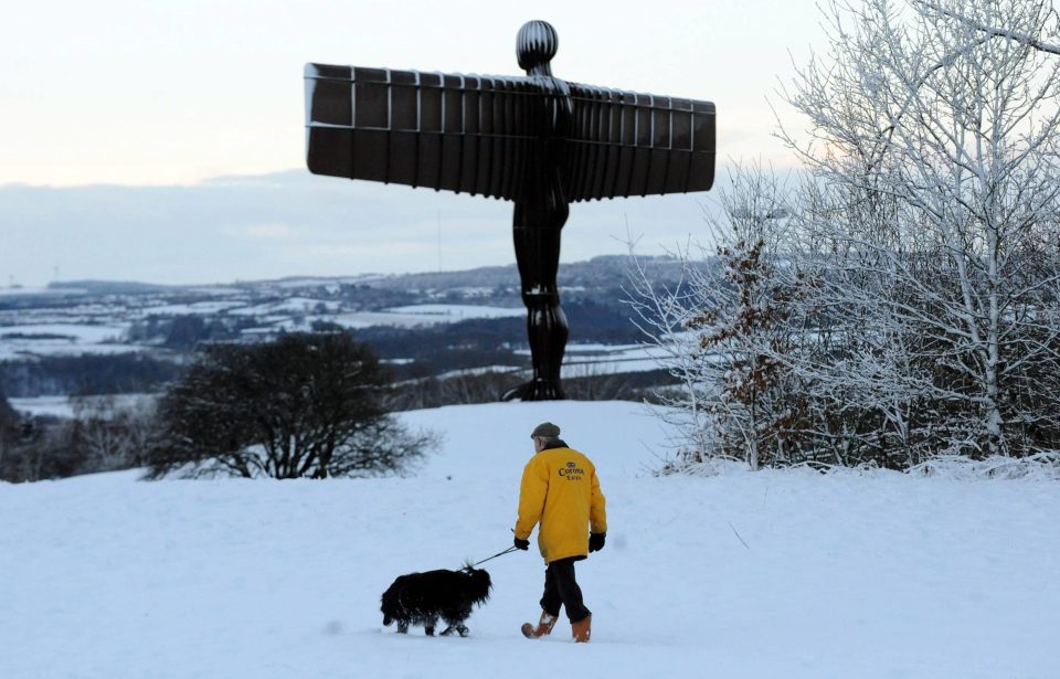 A dog walker admires the winter scenery at the Angel of the North in Gateshead 