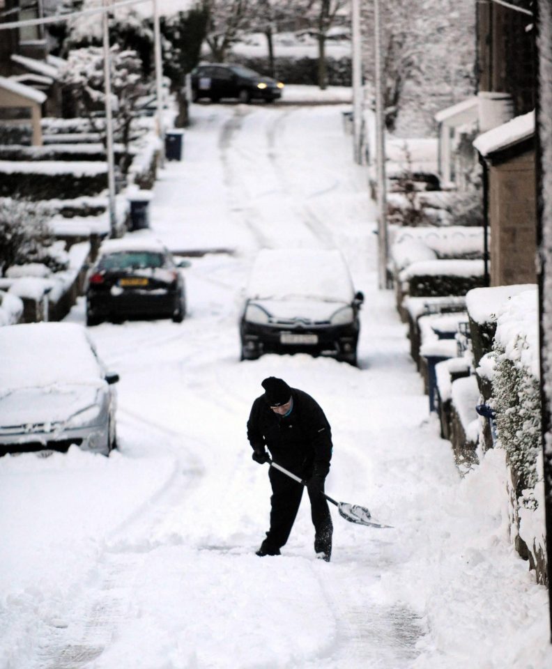 A resident shovels snow from the paths in Eighton Banks, Gateshead
