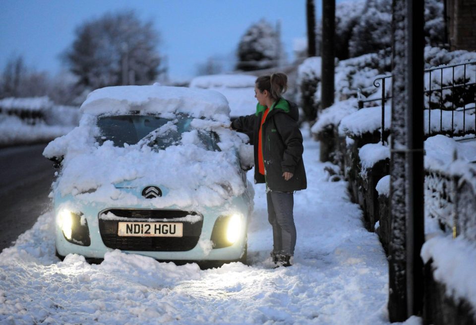 A motorist removes snow from her vehicle in Eighton Banks, Gateshead