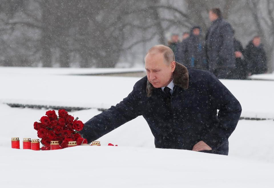 Russian President Vladimir Putin lays flowers during a ceremony at the Piskarevskoye Cemetery in St Petersburg, Russia