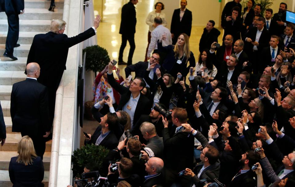 Trump waves as a crowd of people gather snapping pictures of him at the summit