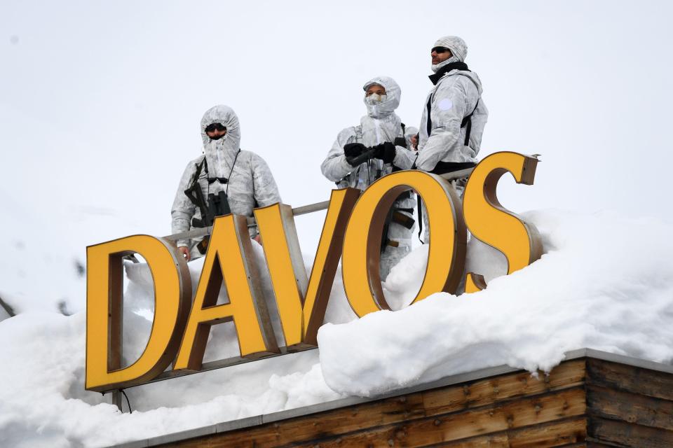 Armed security personnel stand guard on the rooftop of a hotel, next to letters reading "Davos" surrounded by snow, near the Congress Centre 