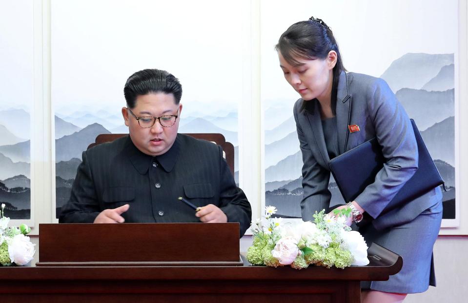 Kim takes a pen from his sister as he prepares to sign the guest book at the Peace House in the DMZ