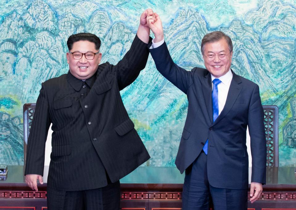 Kim Jong-un and Moon Jae-in raise their hands in celebration after signing an agreement pledging to work towards reunificaiton