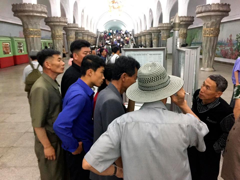 Commuters in Pyongyang gather round to read about the historic meeting