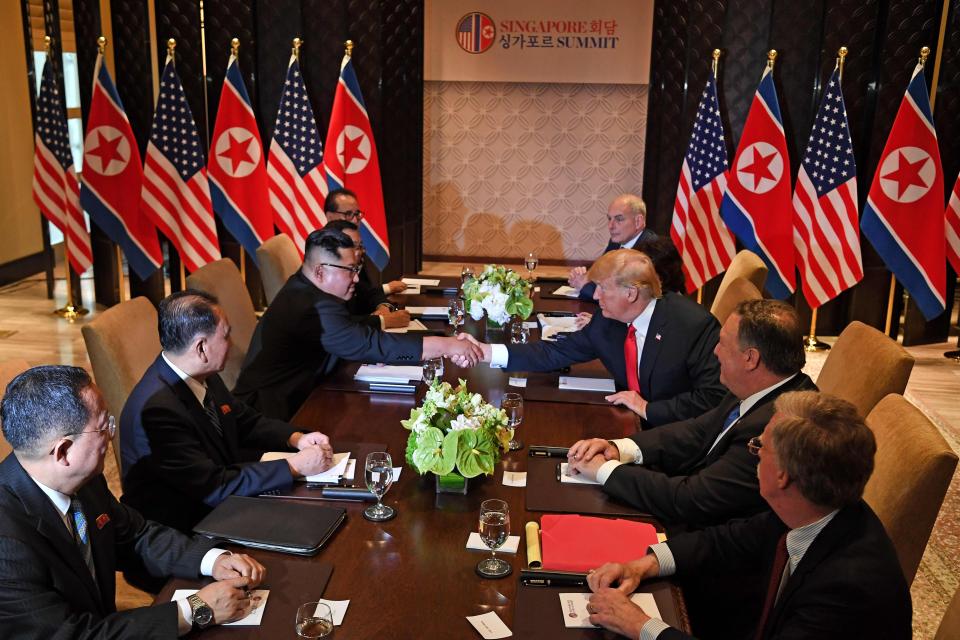  Kim Jong-un and Donald Trump shake hands as they sit down with their respective delegations