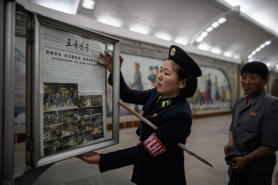  A conductor changes the newspaper to the latest edition showing images of North Korean leader Kim Jong Un in Singapore, at a news stand on a subway platform of the Pyongyang metro