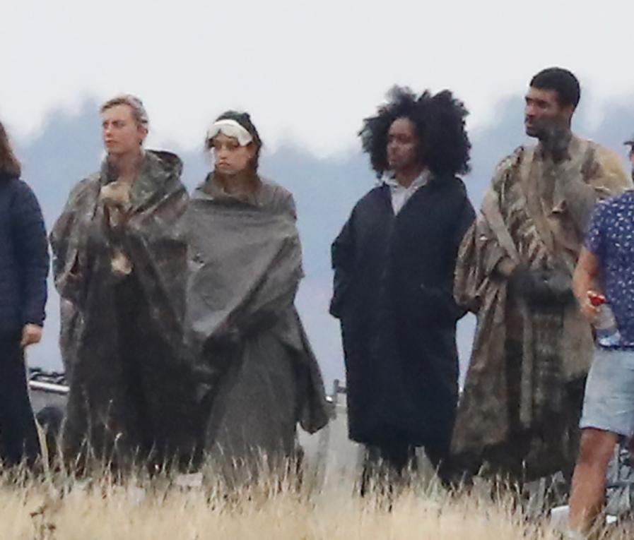 Extras were pictured standing around in their utilitarian style costumes