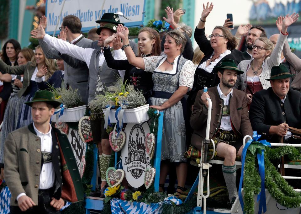People wave during a parade as part of the opening ceremony
