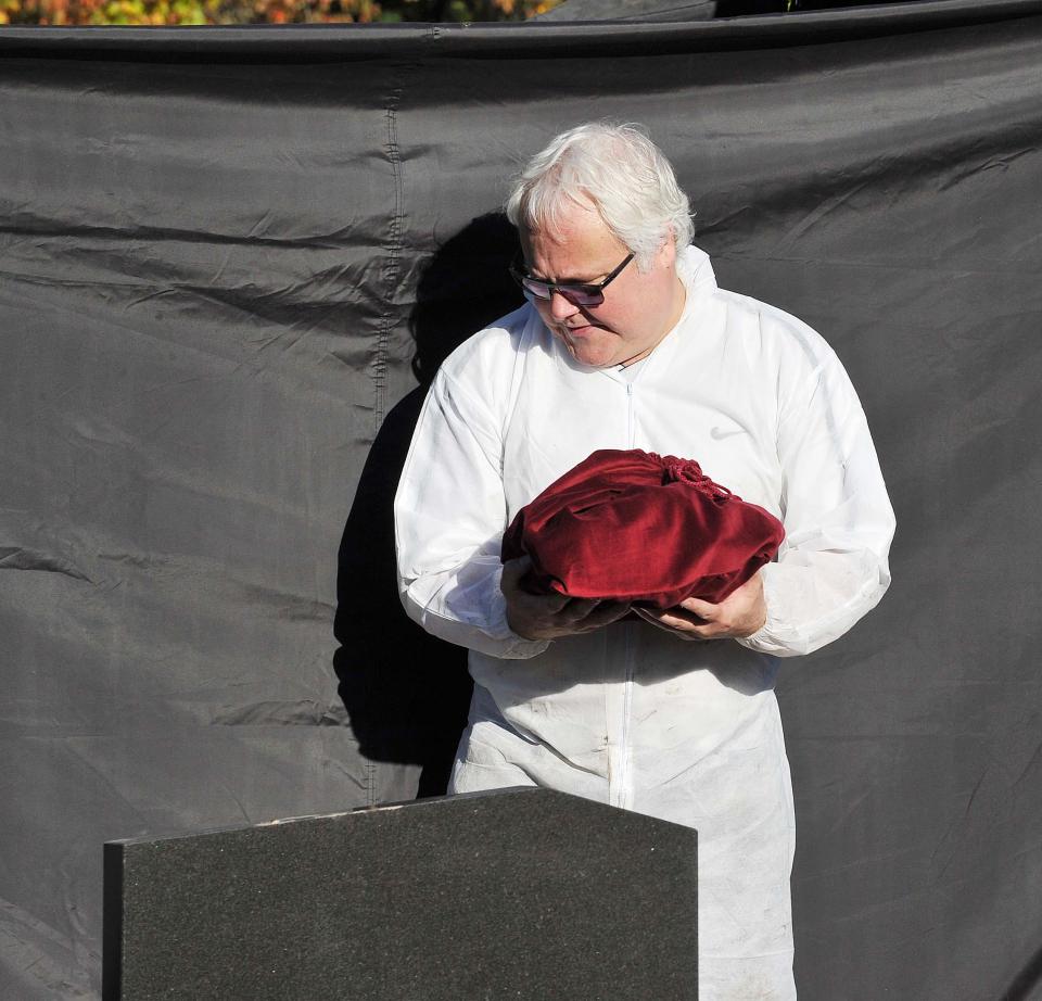 A worker holds a red velvet bag containing remains of Pauline at the service today