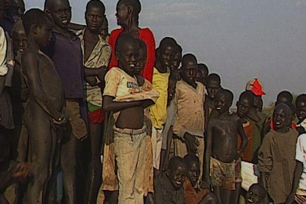 Emmanuel Jal, in the middle pulling up his white t-shirt, with other so called Lost Boys