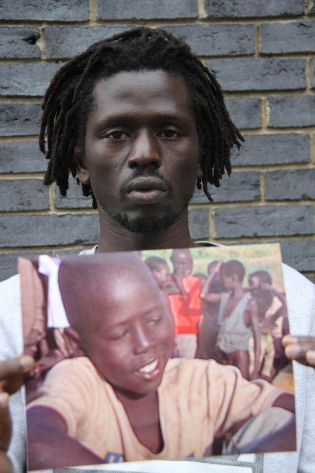 Emmanuel holding a photograph of himself as a child 