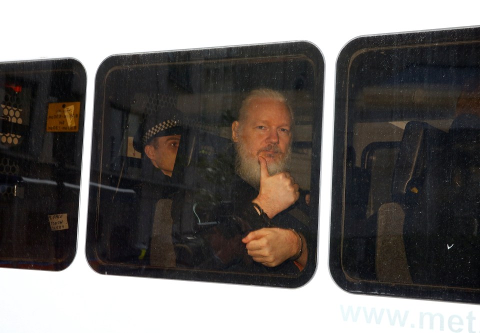 Assange gestures to the media as he gets hauled to the Westminster Magistrates' Court 