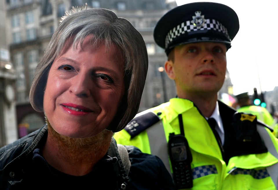 A police officer detains a climate change activist wearing a mask depicting Britain's Prime Minister Theresa May, at Oxford Circus