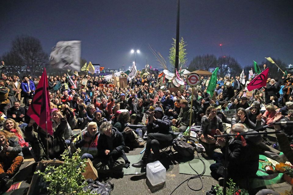  Demonstrators sitting and waving flags bearing the logo of the environmentalist group