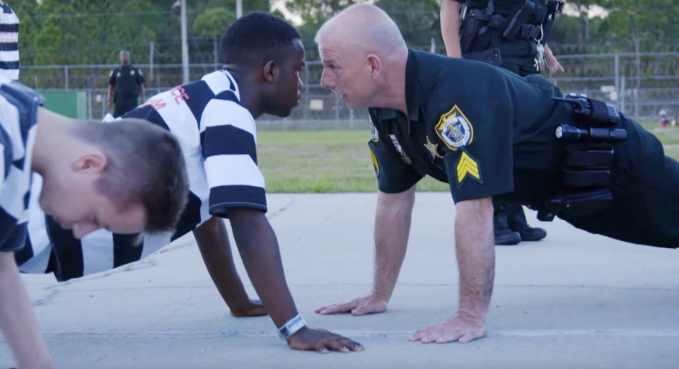 Another teenager is seen doing a press-up as punishment, with a guard just inches from his face