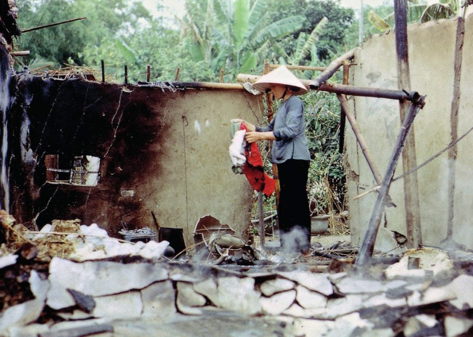  An old Vietnamese woman picks through the remains of her destroyed home after it was razed to the ground in the fighting
