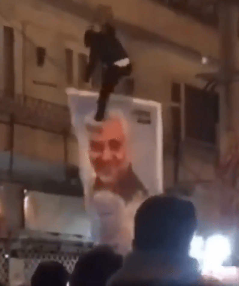  An Iranian kicks a poster of Qasem Soleimani during anti-government protests