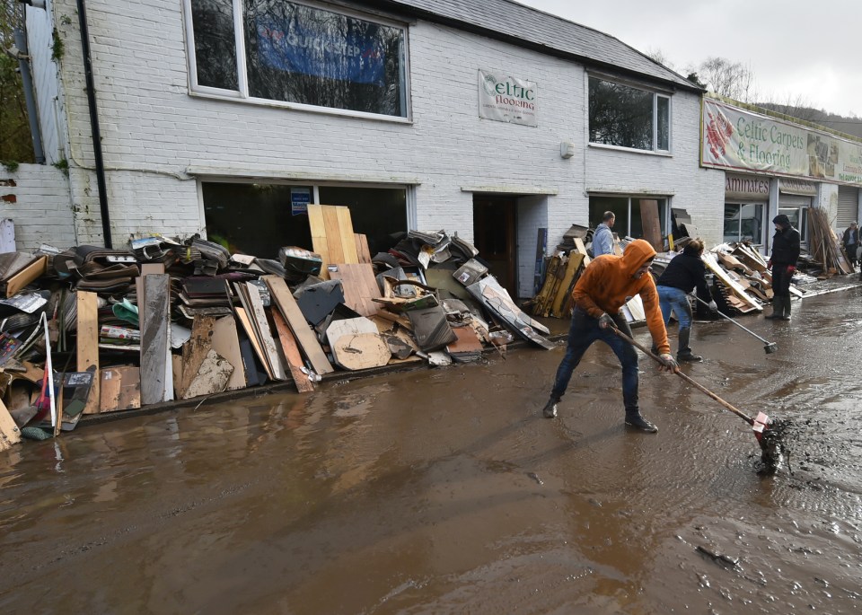 A staff member cleaning outside the Celtic Flooring store, which has been damaged by floodwater in Nantgarw, south Wales