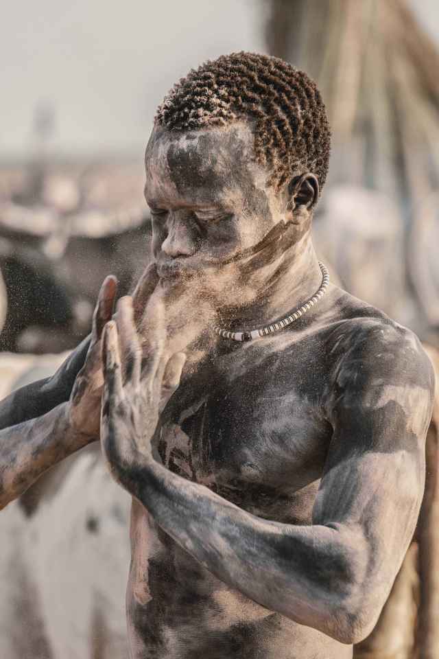 A member of the Mundari tribe covering himself in ashes of fire