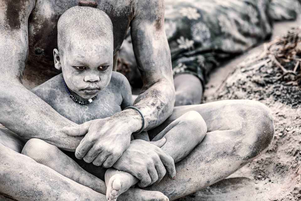 A Mundari boy protected by his mother