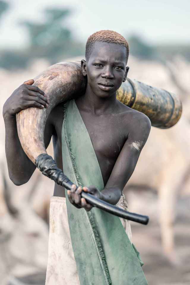 A young Mundari man holding a horn