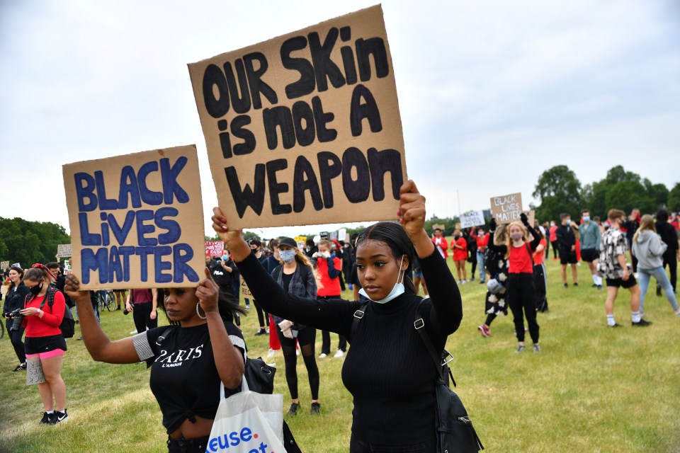  A woman holds up a placard as she marches through the park