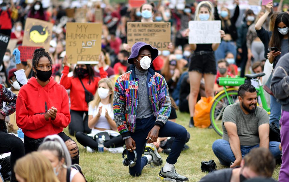  A man is pictured taking a knee in the crowd as he protests against police racism