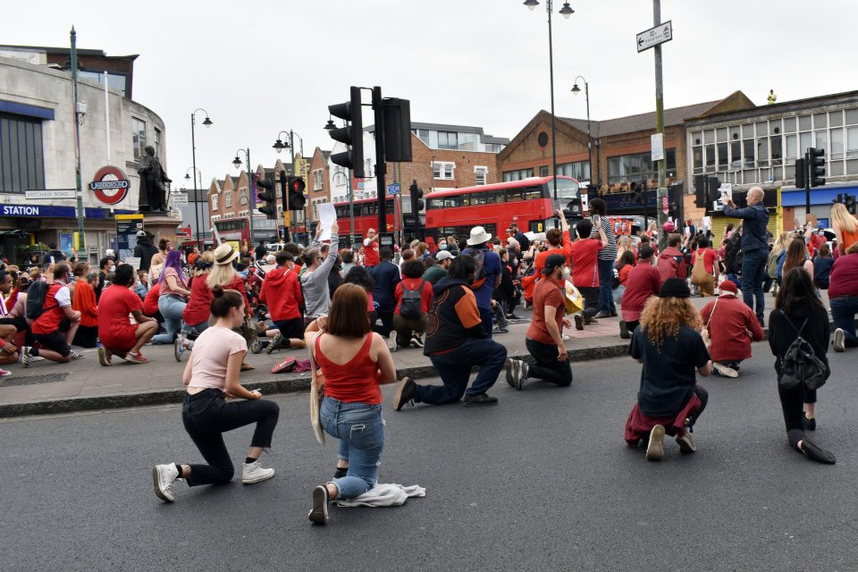  Demonstrators, wearing an item of red, took a knee in the road outside the south London station