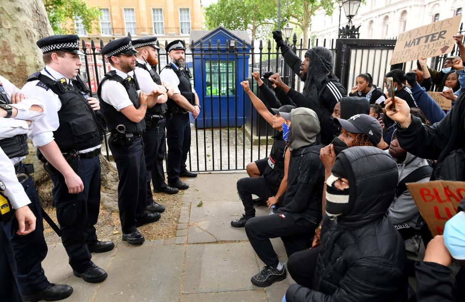  Protesters take a knee in front of a line of police officers amid the protest