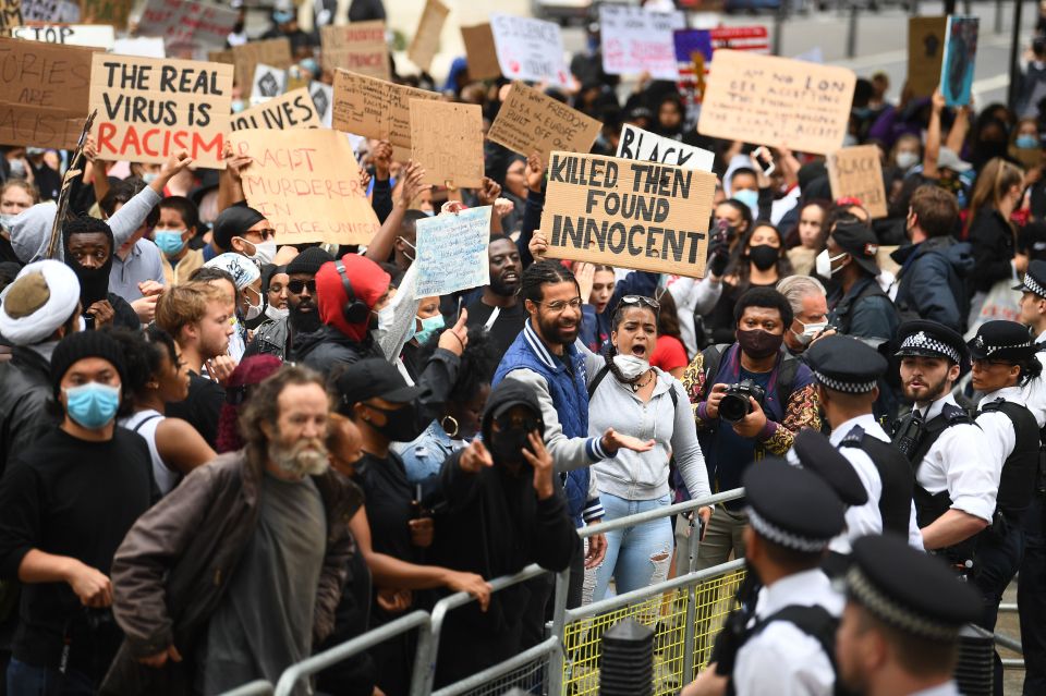 People hold signs during a Black Lives Matter protest rally at the gates of Downing Street
