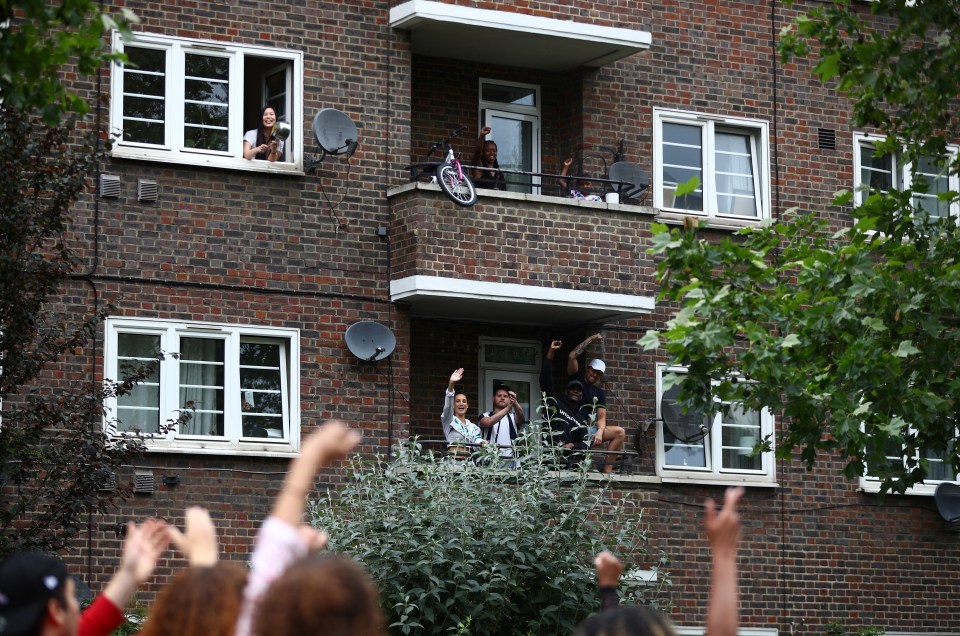 People raise their fists and clap from their balconies and windows as demonstrators pass by