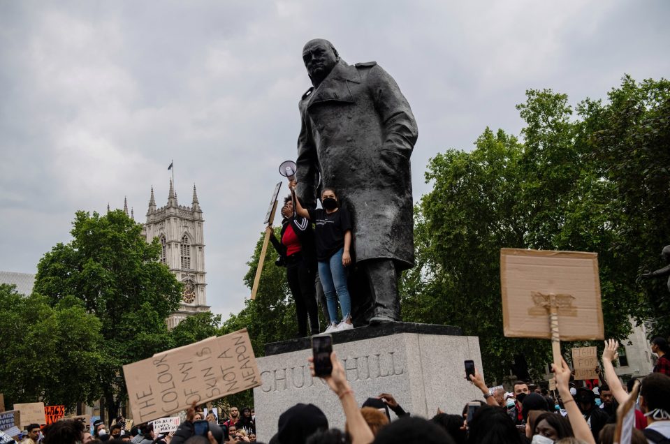  Protesters standing on a statue of Churchill speak to crowds