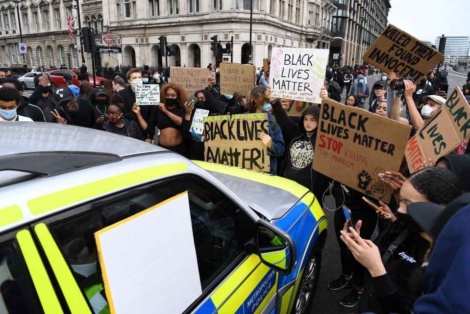 Protesters gather around a police car