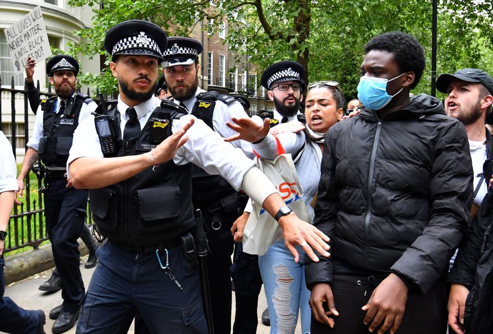  Cops hold back protesters walking through the streets of central London