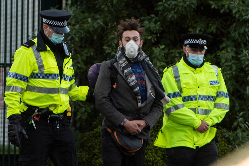 A man in a face covering is led away by police in Knowsley, Liverpool 