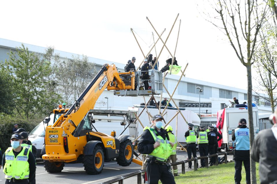 Protesters in bamboo are taken down by the police today outside the printing works