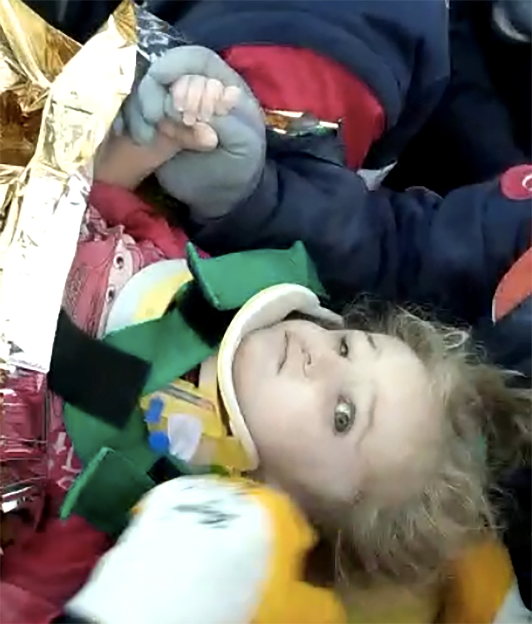 The brave three-year-old clasps her fist tightly round her rescuers' thumb