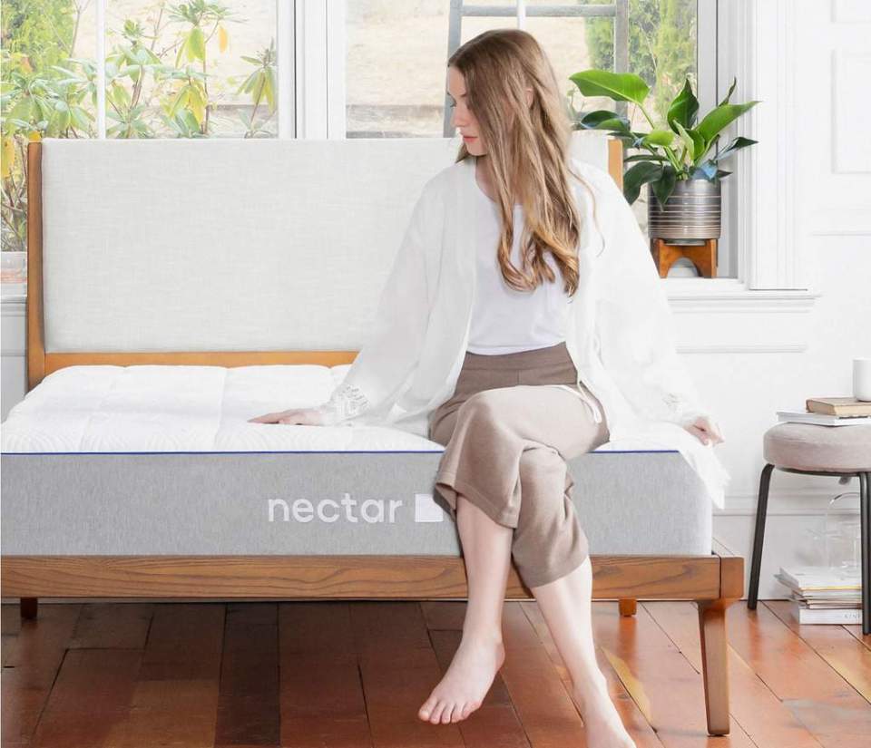 Woman sitting on a Nectar mattress.