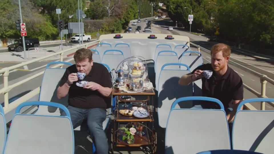 Prince Harry and James Corden having tea on a double-decker bus.
